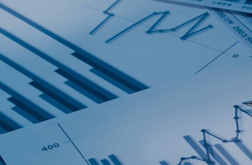 Blue-tinted image of overlapping graphs and bar charts on paper, conveying data analysis and business analytics theme.
