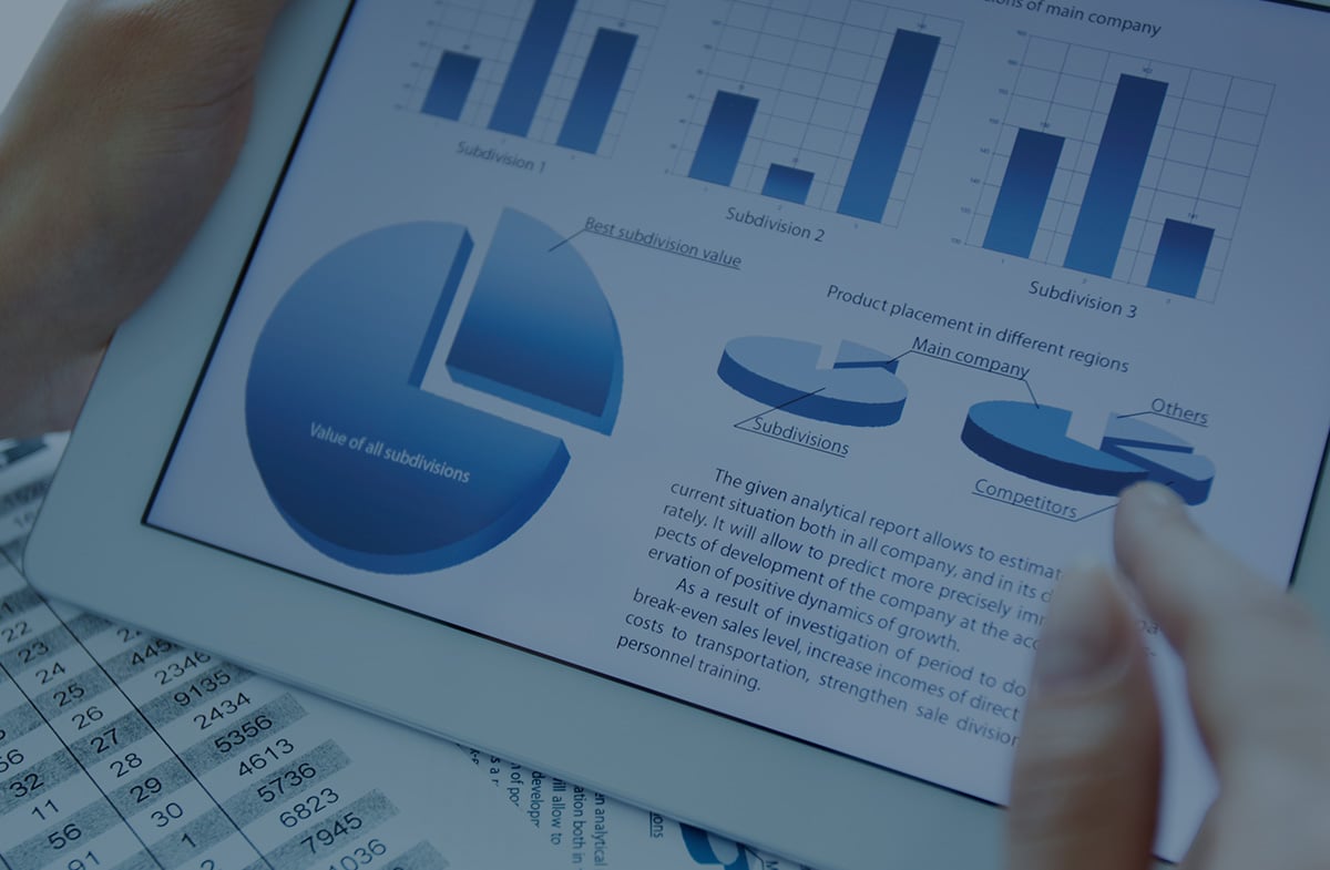 Hand interacting with tablet displaying pie charts, bar graphs, and business report