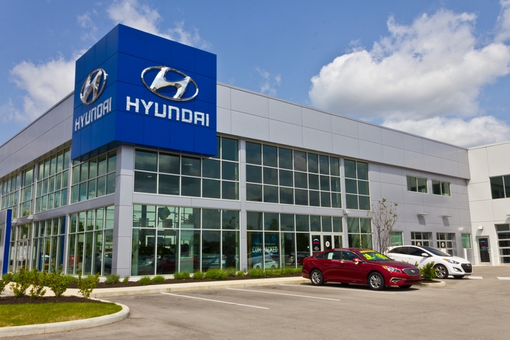Hyundai car dealership exterior with blue sign and parked cars