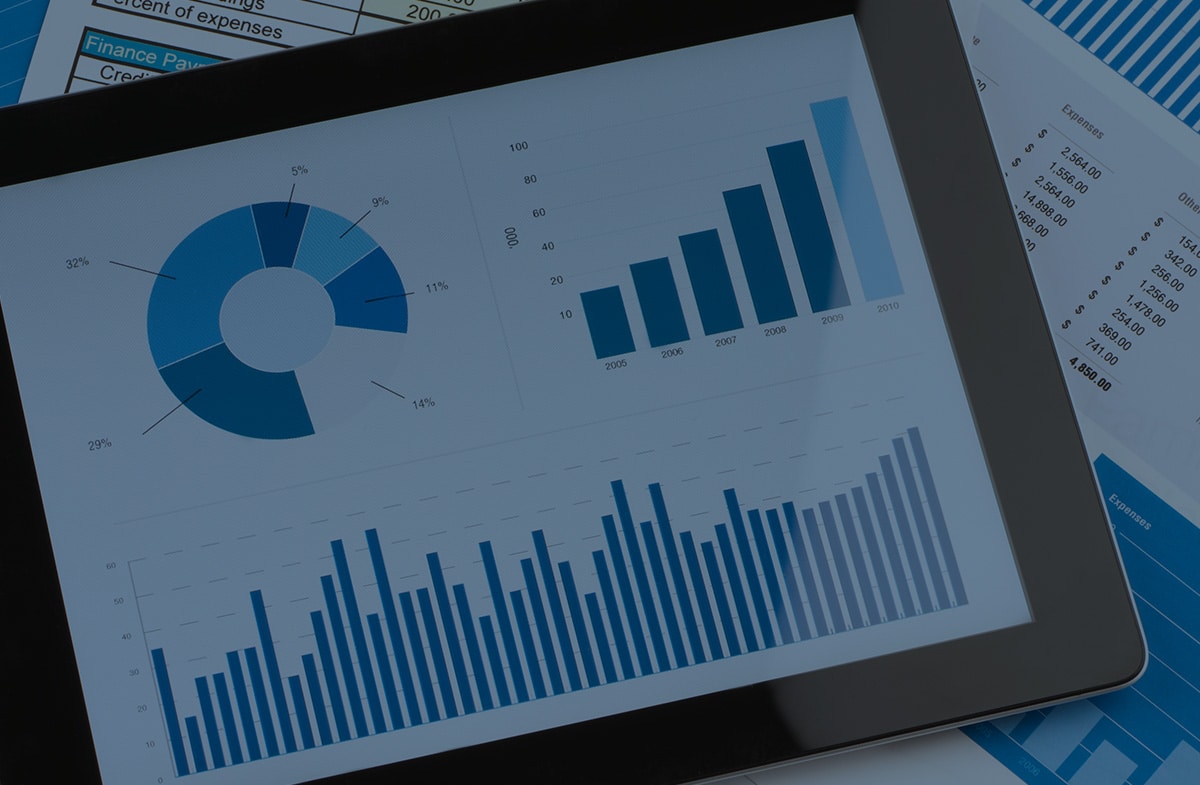 Tablet displaying pie chart and bar graphs with financial documents in background