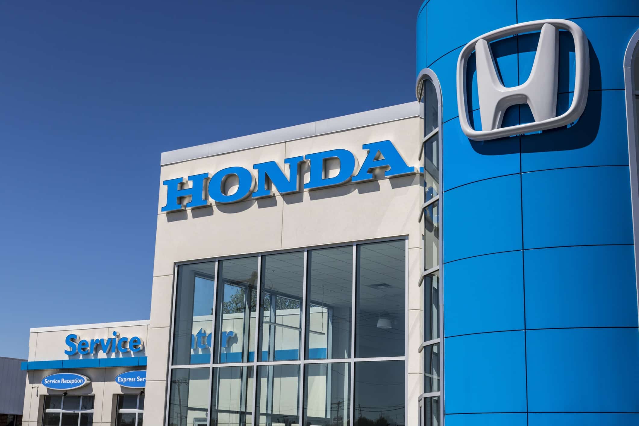 Honda service center exterior in Kansas City, Missouri, featuring signage and service vehicles in the parking lot.