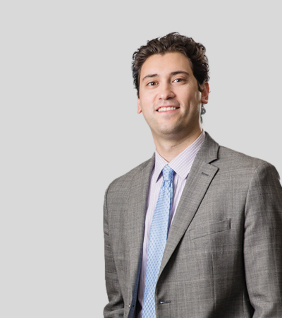 Man in light gray suit with blue tie, slight smile.