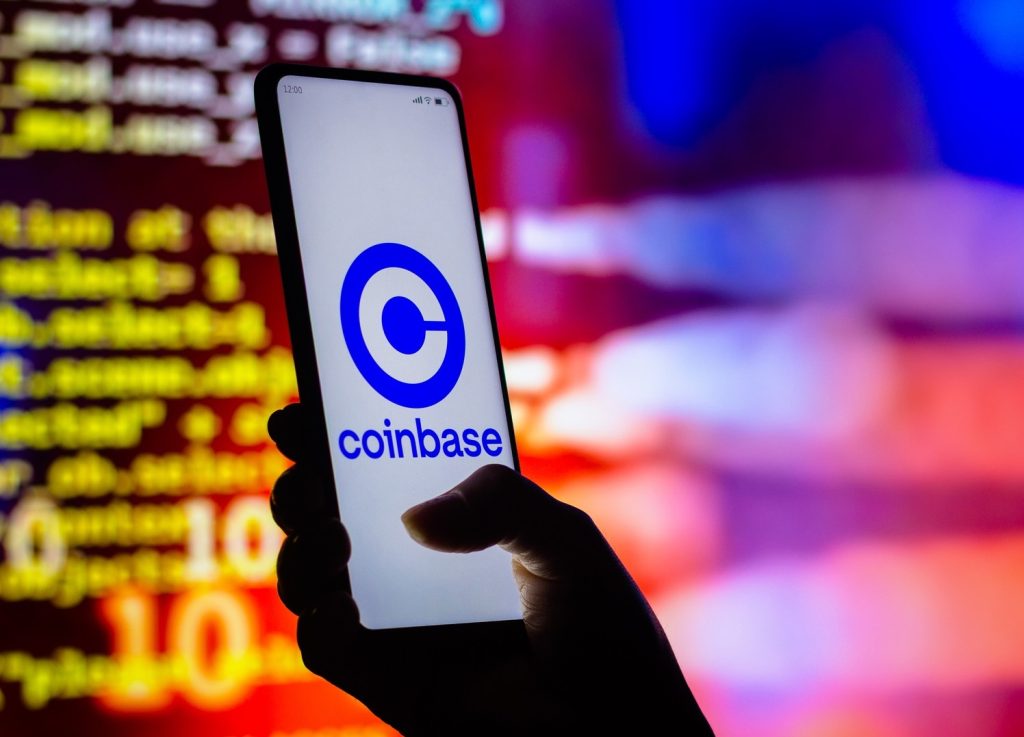 Smartphone displaying Coinbase app logo with digital market background.