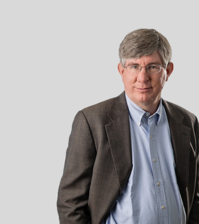 Geoffrey C. Jarvis Professional headshot of older male attorney wearing glasses and brown jacket.
