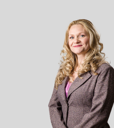 Allyson M. Rosseel: Studio portrait of a woman with curly hair wearing light blazer