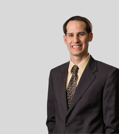 Brian W. Thomer: Studio portrait of a man in dark suit with patterned tie