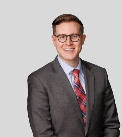 Matthew T. Macken bioimage: Studio portrait of a man wearing glasses and gray suit