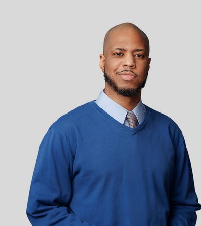 Brian Manigault: Studio portrait of a man wearing blue sweater and collared shirt