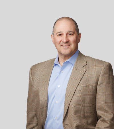 Erik J. Carrozza: Studio portrait of a man in tan blazer and blue shirt