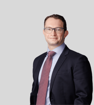 Nathan A. Hasiuk image Man with glasses in dark suit and red tie, neutral expression.