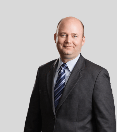 Tyler S. Graden image Bald man in dark suit with striped tie, slight smile.