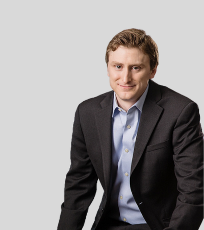 Ethan Barlieb image Man in dark blazer with open collar shirt, smiling.