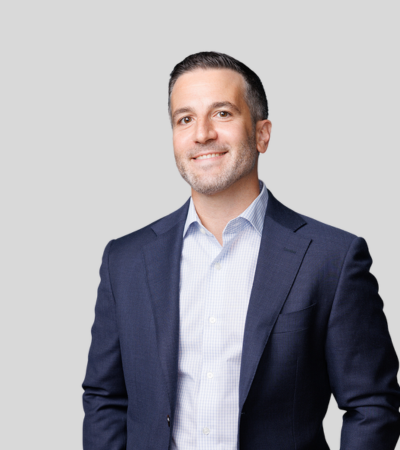Joshua A. Materese image Man in navy blazer with open collar shirt, smiling.