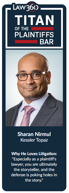 Professional headshot of a man wearing glasses, suit, and pink tie against a neutral background.